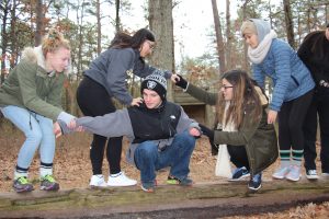 A group of students trying to balance on a fallen log.